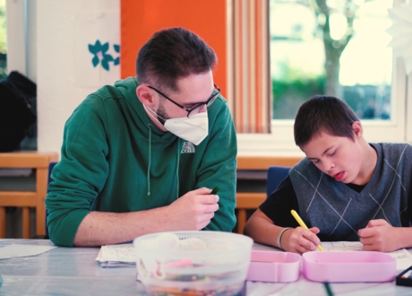 Das Bild zeigt den Heilerziehungspfleger in Ausbildung mit einem Jungen beim Malen.