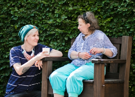 Junge Dame hockt neben einer Dame, die auf einem Stuhl sitzt