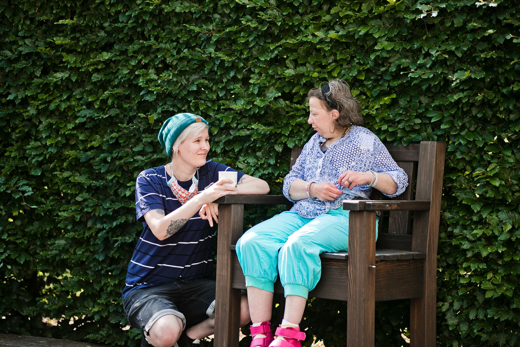 Junge Dame hockt neben einer Dame, die auf einem Stuhl sitzt